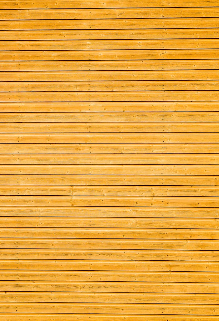 Close-up of yellow wooden plank wall with horizontal lines creating a classic texture.