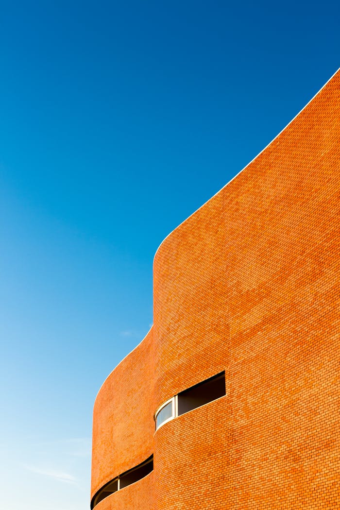 Curved brick building facade against a vibrant blue sky.